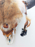 Closeup section of Bison skull wall hanging covered in red coyote fur showing detail of fur, feathers, and leather tassels.