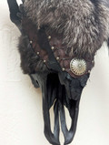 Closeup section of Bison skull wall hanging covered in dark silver fox fur showing detail of fur and leather accents with decorative rivets.