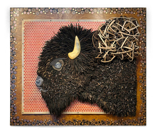 Two-dimensional American bison head constructed from repurposed hat felt strips and pieces and arranged to mimic the fur patterns on a bison. Mounted on wood with small circular patterned background. 
