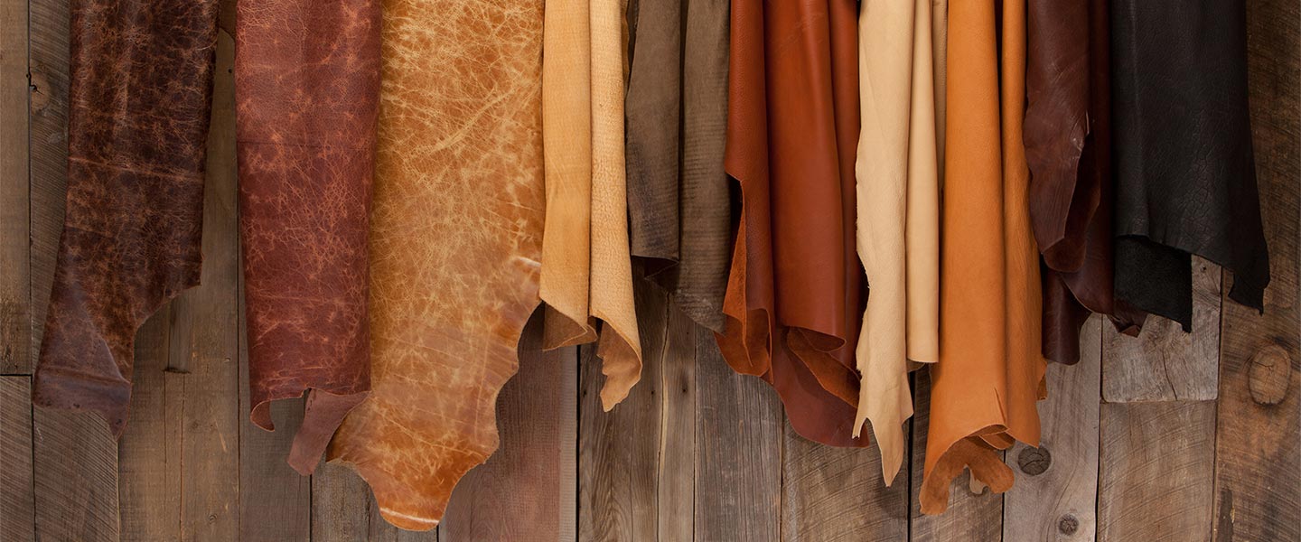 Collection of Buffalo leather hides in various colors and finishes hanging on a fence