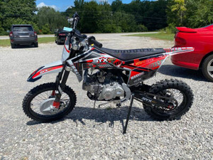 The image showcases the SYX MotoPro PAD190-V2 190cc Pit Bike in one of its two available color options: Red with Grey or Teal with Black. The bike features a sleek and modern design with upgraded plastic kits and a new muffler with a chrome pipe and anti-scalding sheet. The inverted front fork and SX rear shock absorber are prominently displayed, highlighting the bike's advanced suspension system. The heavy-duty black steel rims with deep-teeth pattern off-road tires and hydraulic disc brakes are visible, emphasizing the bike's durability and safety features. The handlebar with a built-in air filter and the SY new forged triple clamp add to the bike's premium feel. The SY V2 double tube cradle frame and SY steel swing arm (knife-shape) are also showcased, underscoring the bike's robust construction. Overall, the image captures the essence of a high-performance, stylish, and durable pit bike ready for any off-road adventure. The image showcases the SYX MotoPro PAD190-V2 190cc Pit Bike in one of its two available color options: Red with Grey or Teal with Black. The bike features a sleek and modern design with upgraded plastic kits and a new muffler with a chrome pipe and anti-scalding sheet. The inverted front fork and SX rear shock absorber are prominently displayed, highlighting the bike's advanced suspension system. The heavy-duty black steel rims with deep-teeth pattern off-road tires and hydraulic disc brakes are visible, emphasizing the bike's durability and safety features. The handlebar with a built-in air filter and the SY new forged triple clamp add to the bike's premium feel. The SY V2 double tube cradle frame and SY steel swing arm (knife-shape) are also showcased, underscoring the bike's robust construction. Overall, the image captures the essence of a high-performance, stylish, and durable pit bike ready for any off-road adventure.