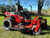 2025 Toro 60" TITAN MyRIDE Zero Turn Mower (76614) showcasing its rugged, commercial-grade design and premium features. The mower features a heavy-duty IronForged® 10-gauge steel cutting deck, built to withstand tough mowing conditions with reinforced belts and massive spindles. The commercial-style I-beam front end highlights its extreme durability and strength, while the 22" rear tires with aggressive treads ensure maximum traction on any terrain. The MyRIDE® Suspension System is prominently displayed, isolated from the frame to provide a smooth, comfortable ride. The treaded 13" front casters add stability and a rugged aesthetic, and the 20" gaming-style seat offers exceptional comfort for long mowing sessions. The rubber discharge chute is visible, designed to flex and protect landscaping while delivering a clean cut. This image captures the Toro TITAN's powerful Kohler KT745 26 HP (747cc) engine, pro-level drop pin height adjustment system, and overall dominance as a top-tier residential zero-turn mower. Perfect for homeowners seeking commercial-grade performance and comfort in a mower.