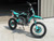 SYX MotoPro PAD190-V2 190cc Pit Bike in one of its two available color options: Red with Grey or Teal with Black. The bike features a sleek and modern design with upgraded plastic kits and a new muffler with a chrome pipe and anti-scalding sheet. The inverted front fork and SX rear shock absorber are prominently displayed, highlighting the bike's advanced suspension system. The heavy-duty black steel rims with deep-teeth pattern off-road tires and hydraulic disc brakes are visible, emphasizing the bike's durability and safety features. The handlebar with a built-in air filter and the SY new forged triple clamp add to the bike's premium feel. The SY V2 double tube cradle frame and SY steel swing arm (knife-shape) are also showcased, underscoring the bike's robust construction. Overall, the image captures the essence of a high-performance, stylish, and durable pit bike ready for any off-road adventure. SYX MotoPro PAD190-V2 190cc Pit Bike in one of its two available color options: Red with Grey or Teal with Black. The bike features a sleek and modern design with upgraded plastic kits and a new muffler with a chrome pipe and anti-scalding sheet. The inverted front fork and SX rear shock absorber are prominently displayed, highlighting the bike's advanced suspension system. The heavy-duty black steel rims with deep-teeth pattern off-road tires and hydraulic disc brakes are visible, emphasizing the bike's durability and safety features. The handlebar with a built-in air filter and the SY new forged triple clamp add to the bike's premium feel. The SY V2 double tube cradle frame and SY steel swing arm (knife-shape) are also showcased, underscoring the bike's robust construction. Overall, the image captures the essence of a high-performance, stylish, and durable pit bike ready for any off-road adventure.