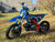 Denago MX1 Dirt Bike, a sleek and powerful entry-level dirt bike designed for riders transitioning to manual shifting. The bike features a 107cc air-cooled 4-stroke engine, semi-automatic transmission, and adjustable hydraulic suspension. Key highlights include hydraulic disc brakes, electric start with backup kickstarter, folding brake levers, and premium components like a gold drive chain and CNC anodized aluminum parts. The bike's powder-coated black wheels and stainless steel exhaust add to its rugged yet stylish appearance, making it the perfect choice for off-road adventures.