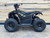 The image features the Denago E-Hawk 6 ATV, a sleek and modern electric ATV designed for kids aged 6 and up. The ATV showcases a bold black finish with multicolored LED lights, giving it a stylish and futuristic look. The rugged all-terrain tires (AT 16 x 8-7) and double A-arm front suspension highlight its capability to handle various terrains, from dirt trails to grassy fields. The handlebar-mounted controls, including the push-button gear selector and keyed ignition, are clearly visible, emphasizing the ATV's user-friendly design. The compact dimensions (51" x 31" x 32.5") and low seat height (23.5") make it perfectly sized for young riders, while the 48V removable lithium-ion battery and 1600W brushless electric motor underscore its eco-friendly and high-performance features. Safety elements like dual hydraulic disk brakes and an anti-theft alarm are subtly integrated into the design. This image captures the essence of the E-Hawk 6 ATV as a safe, fun, and technologically advanced electric vehicle for kids.