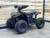 The image features the Denago E-Hawk 6 ATV, a sleek and modern electric ATV designed for kids aged 6 and up. The ATV showcases a bold black finish with multicolored LED lights, giving it a stylish and futuristic look. The rugged all-terrain tires (AT 16 x 8-7) and double A-arm front suspension highlight its capability to handle various terrains, from dirt trails to grassy fields. The handlebar-mounted controls, including the push-button gear selector and keyed ignition, are clearly visible, emphasizing the ATV's user-friendly design. The compact dimensions (51" x 31" x 32.5") and low seat height (23.5") make it perfectly sized for young riders, while the 48V removable lithium-ion battery and 1600W brushless electric motor underscore its eco-friendly and high-performance features. Safety elements like dual hydraulic disk brakes and an anti-theft alarm are subtly integrated into the design. This image captures the essence of the E-Hawk 6 ATV as a safe, fun, and technologically advanced electric vehicle for kids.