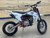 The image showcases the 2025 SSR SR140RB Pit Bike in a rugged, off-road setting, highlighting its powerful design and advanced features. The pit bike features a white color option, adjustable inverted hydraulic front forks, and steel wheels with 70/100-17 front tires and 90/100-14 rear tires. The dual disc brakes are prominently displayed, emphasizing the bike's safety and control features. The adjustable mono shock rear suspension and double bar steel frame are visible, showcasing the bike's durability and stability. This image perfectly captures the SSR SR140RB's blend of performance, safety, and style, making it an ideal choice for off-road enthusiasts.