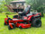 Toro 50" TimeCutter Max MyRide Zero Turn Mower (77502), highlighting its innovative MyRIDE® Suspension System with a close-up of the large spring coil. This feature isolates the operator from rough terrain, providing a smooth and comfortable ride while mowing. The mower’s heavy-duty steel IronForged® Deck is prominently displayed, emphasizing its durability and ability to handle tough mowing conditions. The beefy hybrid-tread rear tires are shown for maximum traction, ensuring the mower can navigate any terrain without damaging the turf. Additionally, the image highlights the spray-blocking fenders, which prevent debris and water from splashing onto the engine or operator. The automotive-style fuel fill and integrated drain hose are also visible, showcasing the mower’s user-friendly maintenance features. With its ultra-strong, fully tubular steel frame and 23 hp Kawasaki engine, this zero-turn mower is designed for professional-grade performance and residential comfort.