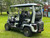 Evolution D-MAX GT4 luxury electric golf cart with forward-facing design, black automotive-grade seats, 10.1-inch touchscreen with CarPlay, 24-speaker audio system, LED lighting, and aluminum wheels, built for performance and style.