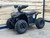 The image features the Denago E-Hawk 6 ATV, a sleek and modern electric ATV designed for kids aged 6 and up. The ATV showcases a bold black finish with multicolored LED lights, giving it a stylish and futuristic look. The rugged all-terrain tires (AT 16 x 8-7) and double A-arm front suspension highlight its capability to handle various terrains, from dirt trails to grassy fields. The handlebar-mounted controls, including the push-button gear selector and keyed ignition, are clearly visible, emphasizing the ATV's user-friendly design. The compact dimensions (51" x 31" x 32.5") and low seat height (23.5") make it perfectly sized for young riders, while the 48V removable lithium-ion battery and 1600W brushless electric motor underscore its eco-friendly and high-performance features. Safety elements like dual hydraulic disk brakes and an anti-theft alarm are subtly integrated into the design. This image captures the essence of the E-Hawk 6 ATV as a safe, fun, and technologically advanced electric vehicle for kids.