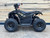 The image features the Denago E-Hawk 6 ATV, a sleek and modern electric ATV designed for kids aged 6 and up. The ATV showcases a bold black finish with multicolored LED lights, giving it a stylish and futuristic look. The rugged all-terrain tires (AT 16 x 8-7) and double A-arm front suspension highlight its capability to handle various terrains, from dirt trails to grassy fields. The handlebar-mounted controls, including the push-button gear selector and keyed ignition, are clearly visible, emphasizing the ATV's user-friendly design. The compact dimensions (51" x 31" x 32.5") and low seat height (23.5") make it perfectly sized for young riders, while the 48V removable lithium-ion battery and 1600W brushless electric motor underscore its eco-friendly and high-performance features. Safety elements like dual hydraulic disk brakes and an anti-theft alarm are subtly integrated into the design. This image captures the essence of the E-Hawk 6 ATV as a safe, fun, and technologically advanced electric vehicle for kids.