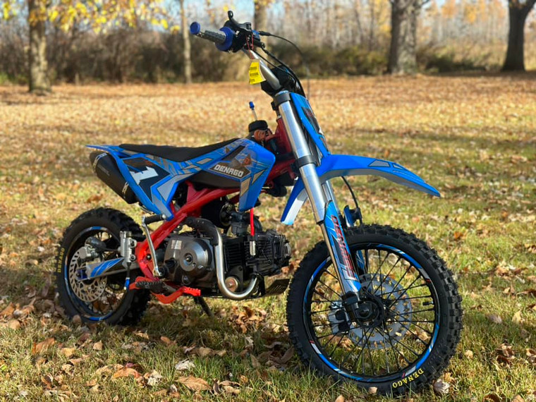 Denago MX1 Dirt Bike, a sleek and powerful entry-level dirt bike designed for riders transitioning to manual shifting. The bike features a 107cc air-cooled 4-stroke engine, semi-automatic transmission, and adjustable hydraulic suspension. Key highlights include hydraulic disc brakes, electric start with backup kickstarter, folding brake levers, and premium components like a gold drive chain and CNC anodized aluminum parts. The bike's powder-coated black wheels and stainless steel exhaust add to its rugged yet stylish appearance, making it the perfect choice for off-road adventures.