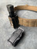 Black ATTACHMENT DM2 MOLLE Attachment with tan belt on gray surface, intended for Mag Carriers.