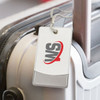 A luggage tag in grey and white attached to a suitcase, featuring a logo on its surface.