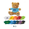 A fluffy brown teddy bear wearing a blue shirt with a logo, surrounded by various colourful t-shirts in different sizes.