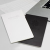 Two Moleskine Volant journals, one white and one black, placed beside a laptop and a notepad. Each has a logo on the cover.