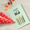 A light green gift card featuring birthday candles, surrounded by a red polka dot party hat and colourful candle numbers.