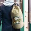 A beige canvas barrel bag with a drawstring, featuring a logo and design related to baseball.