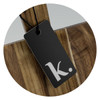 A wooden chopping board with a smooth finish and a black tag attached, featuring a simple logo.