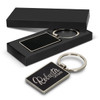 A rectangular key ring with a black texture, presented in a sleek black box, featuring a logo.
