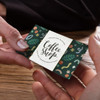 A hand holding a vibrant, full-colour loyalty card featuring a green design with various playful patterns and a logo.