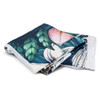 A folded blanket featuring vibrant botanical designs in greens and pinks, with white edges and a logo present.