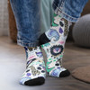Colourful crew socks featuring playful animal patterns, with a black toe and heel, worn by a person in denim jeans.