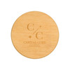 A round bamboo coaster featuring a logo and text for "Capital Core Hotel". The surface is smooth and natural in texture.