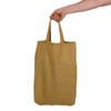A short-handled, mustard yellow tote bag being held by a hand. The bag features an unembellished design and has a logo.