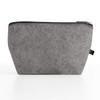 A grey cosmetic pack made of felt material with a zip closure and a small logo on the side.