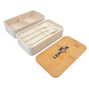 A white lunchbox with a bamboo lid and utensils, featuring a logo. The interior has a divider for compartments.