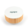 A round speaker and wireless charger with a white top and bamboo base, featuring a logo on the surface.