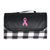 A black and white checkered picnic blanket with a pink ribbon design and a carry handle.