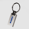 A silver metal keychain with a sleek rectangular design and a circular attachment ring. It has a branding logo.