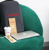 A grey backpack with a logo, a laptop, a coffee cup, and a wooden straw set on a green chair.