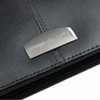 A black leather zippered compendium with a metallic logo embellishment.