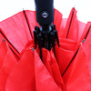 A red umbrella with a black handle and a logo, featuring multiple panels.