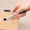 A silver Slimline Retractable Box Cutter held by a hand, positioned above a cardboard box.