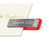 A silver and red LED clip flash drive resting against a cream-coloured card. It features a branding logo.