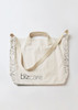 A cream tote bag with a strap, featuring a logo and patterned detailing along the edges.