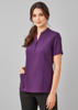 A women's tunic in a rich purple colour with short sleeves and pockets, featuring a button-up placket and a logo.