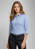 A light blue women's button-up shirt with 3/4 sleeves, featuring a logo and styled with black pants.