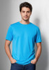 A blue short sleeve men's T-shirt, featuring a round neck and a smooth fabric finish. The model stands casually, hands in pockets.