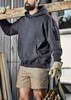 A dark grey unisex multi-pocket hoodie, worn by a person holding a wooden beam, featuring an attached logo.