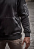A black unisex water-resistant hoodie featuring a pocket and logo, with a sleek design.