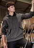 A unisex dark grey water-resistant hoodie with a front pocket and a hood, displayed in a work environment.