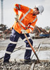An orange long sleeve work shirt with reflective stripes, worn by a worker using a shovel in a construction environment.