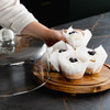 A wooden cake display holding cupcakes, covered with a clear glass dome, featuring white frosting and blueberries.