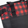 A cooler bag featuring a red and black checkered pattern with black sides and sturdy straps. It has a branding logo.
