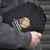 A black tech case with a logo, featuring a rocket design and a handle, held by a person in a grey hoodie.